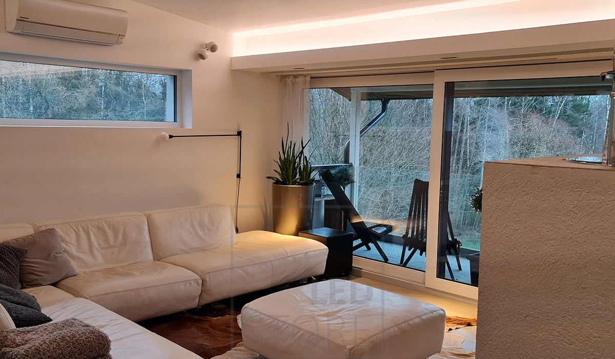 Nedfällbar lampa i vardagsrummet med LED-list som riktas mot taket och skapar vacker stämningsbelysning.